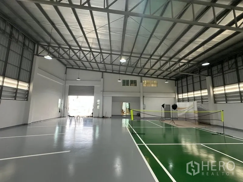 货栈 出售在Pathum Thani - 仓库内部可见卷帘门、通风窗与球场标线。