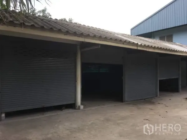 Warehouse for rent in Saphan Sung, Bangkok - Covered loading bays with multiple metal roller shutters and a concrete driveway.