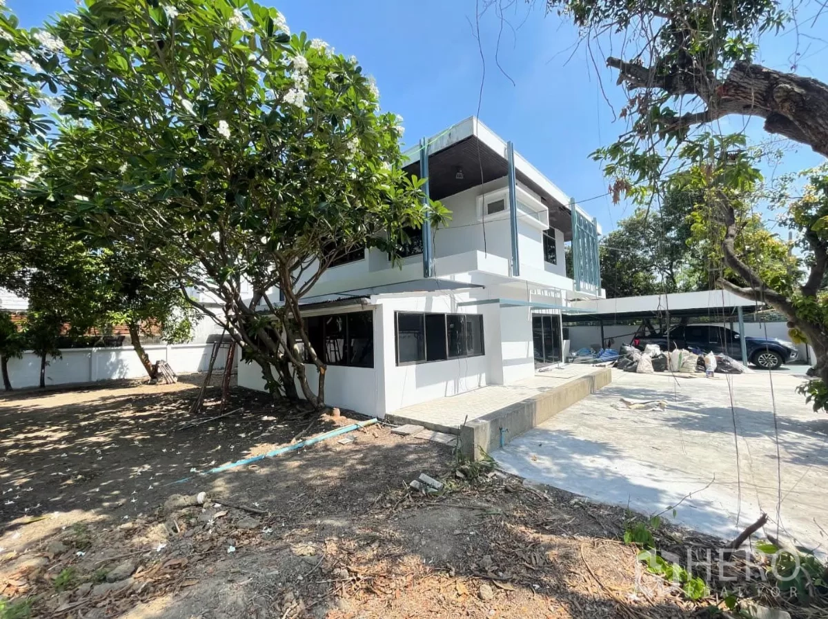 带办公室的家 出租在Din Daeng, Bangkok - 房屋后侧外观，白色两层建筑，铺装露台、花园与院内停车位。