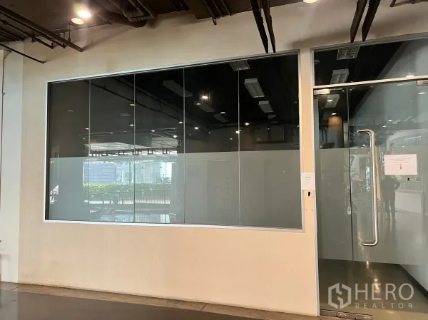 零售空间 出租 - 走廊旁零售铺外观，大片玻璃立面与不锈钢拉手门。