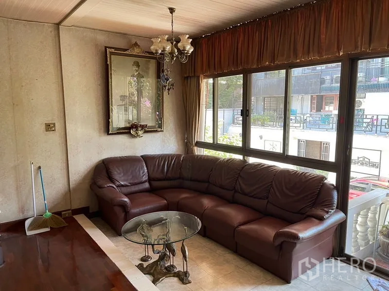 สำนักงานที่บ้าน ให้เช่าในWatthana, Bangkok - มุมนั่งเล่นโซฟาหนังเข้ามุม โคมระย้า และหน้าต่างบานใหญ่