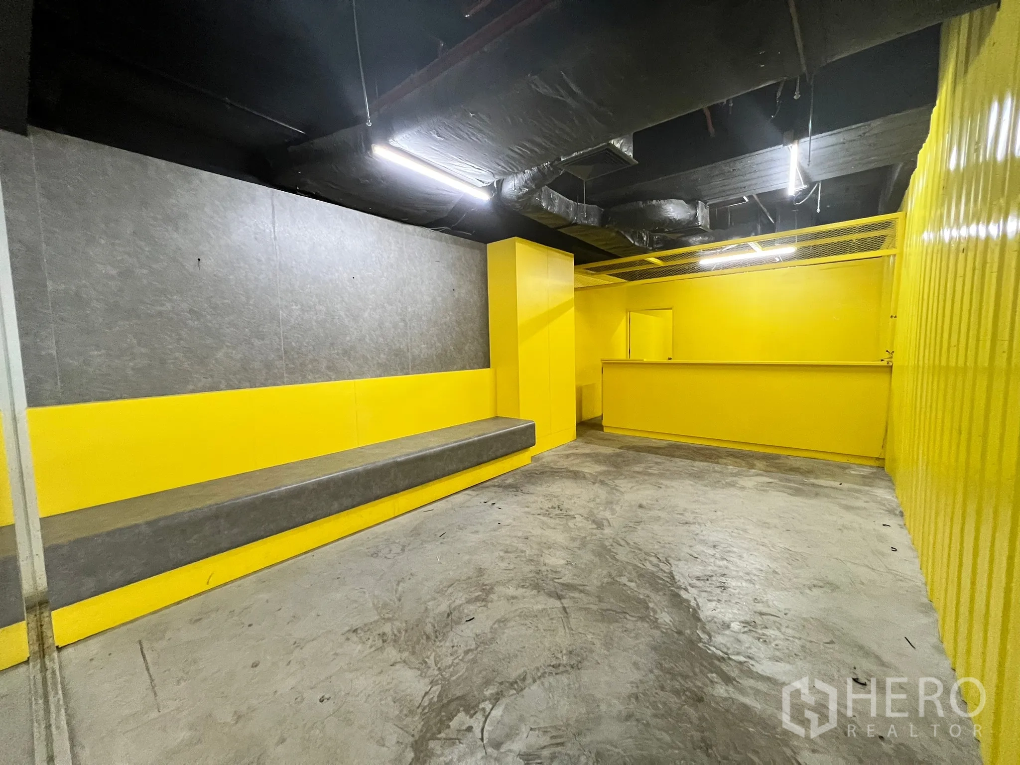 พื้นที่ขายปลีก ให้เช่า - พื้นที่ค้าปลีกแปลนโล่ง มีม้านั่งยาว เคาน์เตอร์บริการ และฝ้าเปิดโชว์งานระบบสีดำ