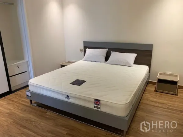 คอนโด ให้เช่า - ห้องนอนหลักสว่าง โปร่ง พร้อมเตียงควีน พื้นไม้ และโต๊ะข้างเตียง