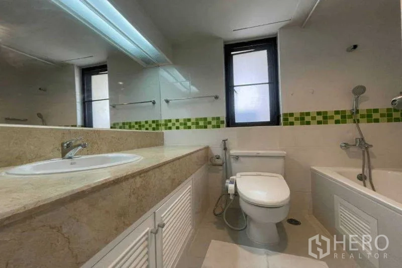 Condominium for rent in Watthana, Bangkok - Bathroom with long stone vanity, bathtub and green mosaic accent tiles.