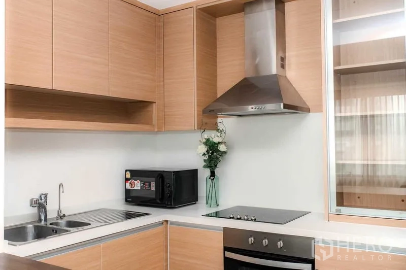 คอนโด ให้เช่าหรือขายในBangkok - ภาพใกล้ครัว แสดงซิงก์ เตาไฟฟ้า และเครื่องดูดควัน