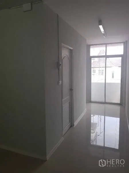 店屋 出租或出售在Lat Phrao, Bangkok - 走廊通向阳台，落地玻璃门引入自然采光。