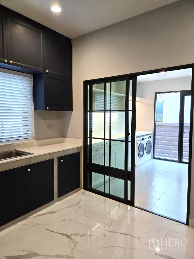 Detached House for rent in Bang Phli, Samut Prakan - Kitchen opening to laundry through black-framed sliding glass door.