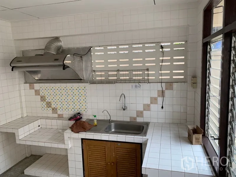 联排别墅 出租在Watthana, Bangkok - 泰式厨房，瓷砖台面、水槽、油烟机与百叶窗。