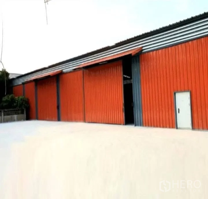 Warehouse for rent in Phaya Thai, Bangkok - Front view of a warehouse with multiple large sliding doors and a wide concrete yard.
