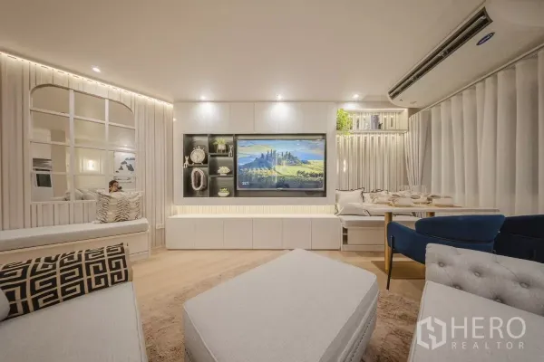 Condominium for rent in Yan Nawa, Bangkok - Feature TV wall with built-in shelves, bench seating and a dining nook framed by full curtains.