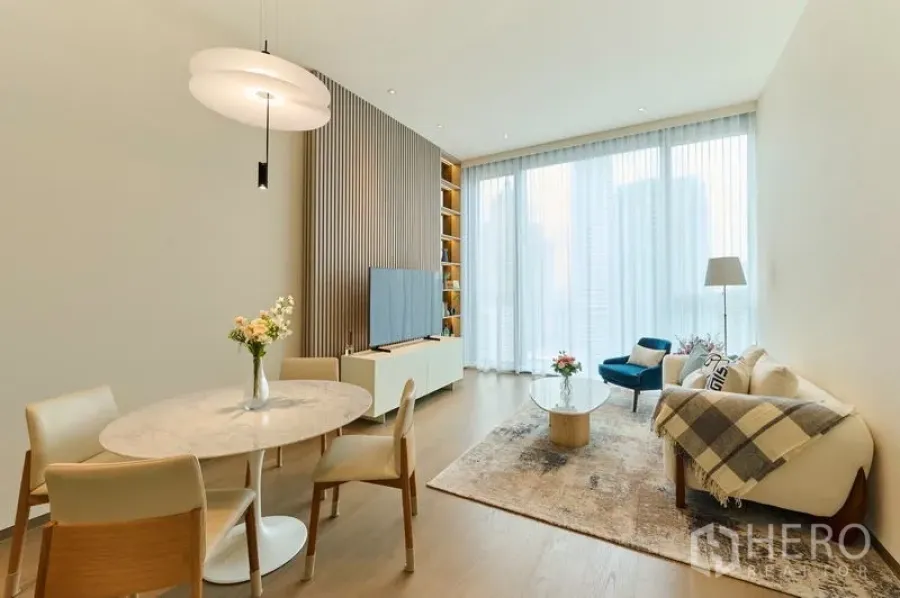 Condominium for rent in Pathum Wan, Bangkok - Sunlit living and dining space with high ceilings and sheer curtains.