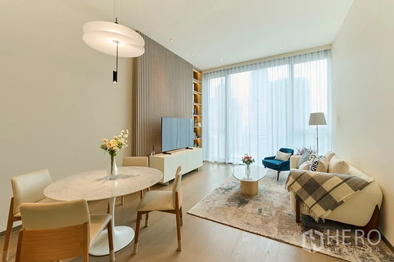 Condominium for rent in Pathum Wan, Bangkok - Sunlit living and dining space with high ceilings and sheer curtains.