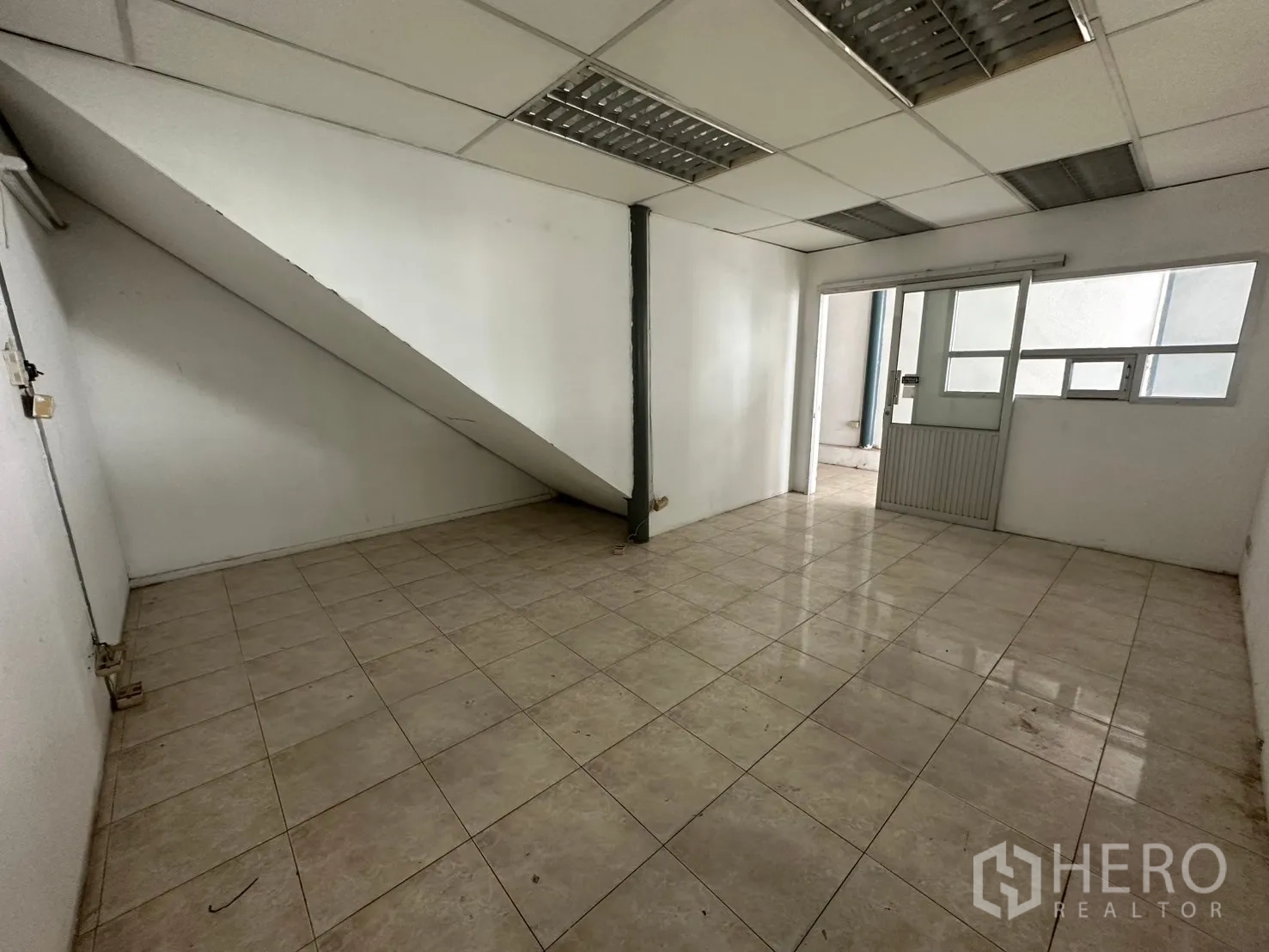 Warehouse for rent in Suan Luang, Bangkok - Compact office under the staircase with sliding windows and tiled floor.