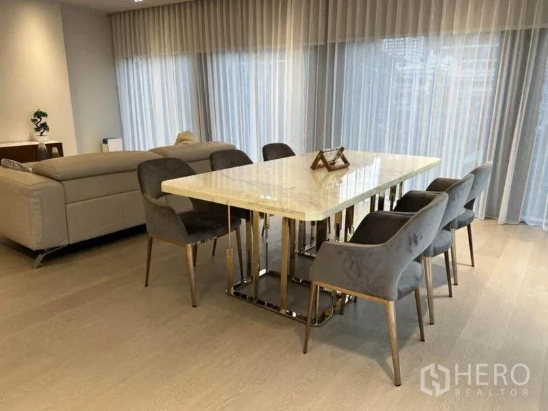 Condominium for rent in Pathum Wan, Bangkok - Six-seat marble dining table set by full-height windows.