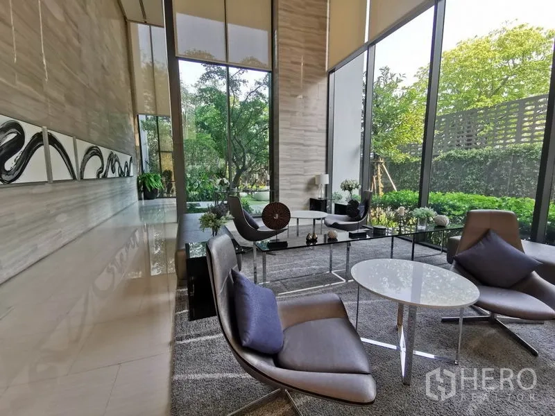Condominium for rent in Khlong Toei, Bangkok - Double-height lobby lounge with contemporary seating and garden views through tall windows.