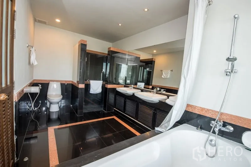 Condominium for rent in Sathon, Bangkok - Modern bathroom with double vanity, walk-in shower and bathtub on black tiled flooring.