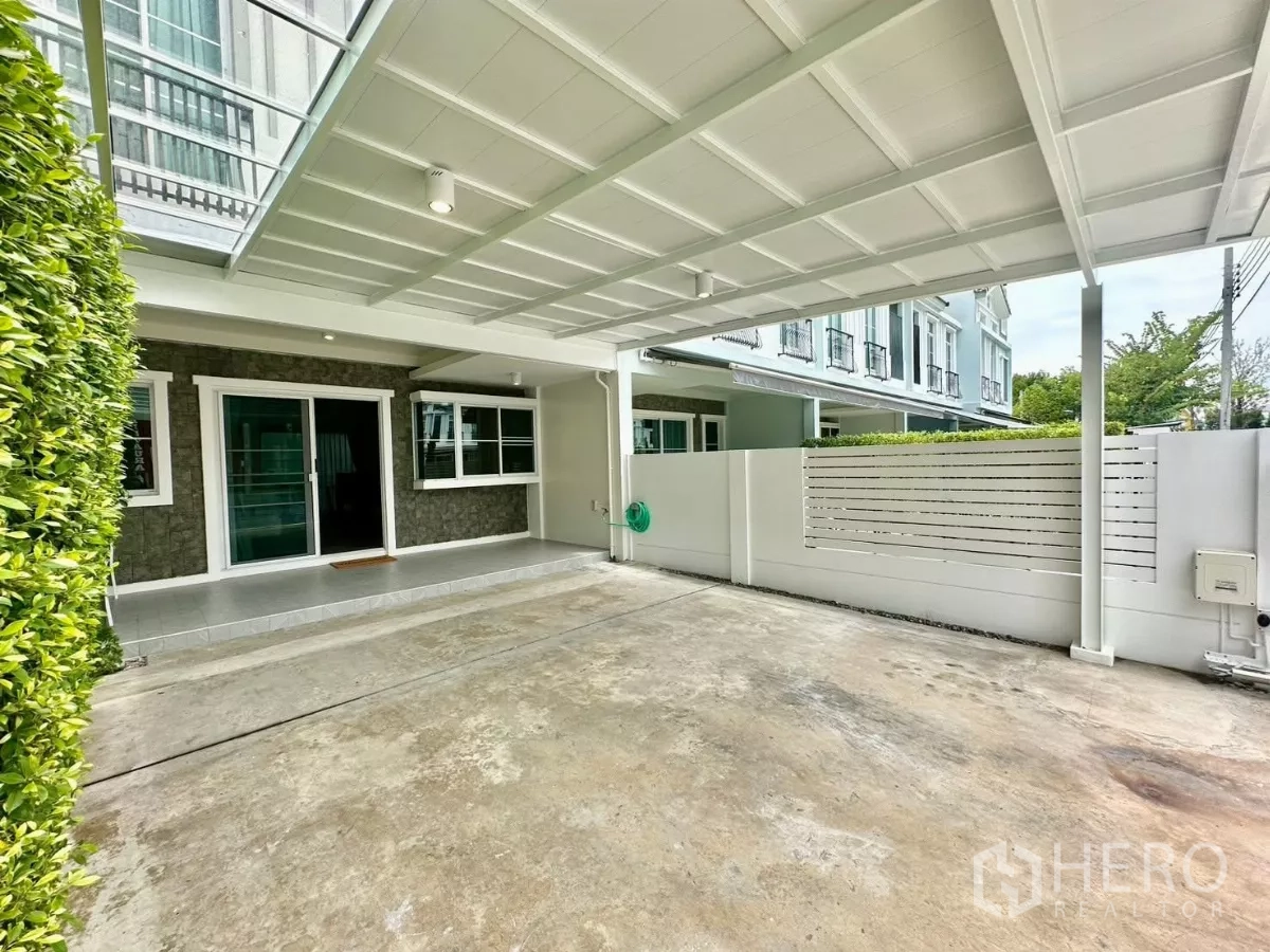 联排别墅 出租在Prawet, Bangkok - 车棚与前露台一角，石质特色墙面与宽阔车道。