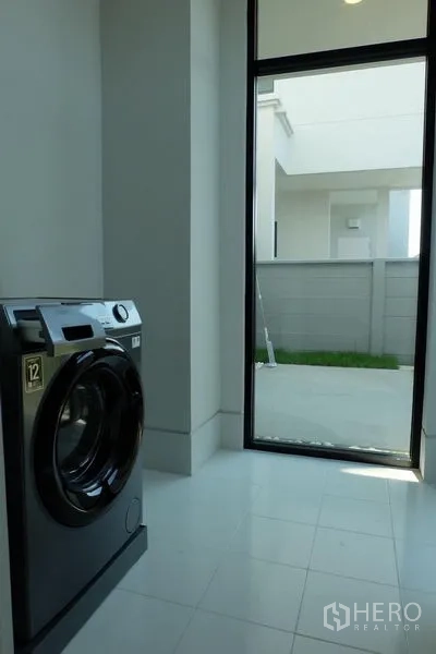 Detached House for rent in Bang Phli, Samut Prakan - Laundry room with front-load washer and a glass door opening to the side yard.