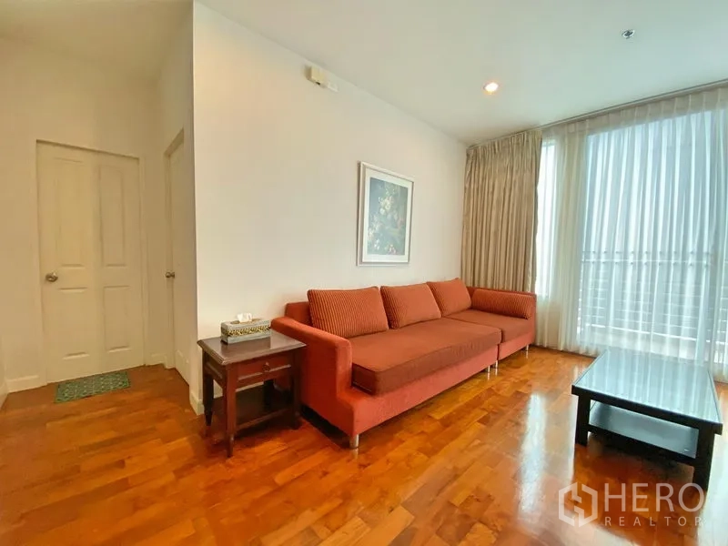 คอนโด ให้เช่าในKhlong Toei, Bangkok - ห้องนั่งเล่นสว่าง โซฟาสีส้ม โต๊ะกลาง และผ้าม่านโปร่งเต็มบาน