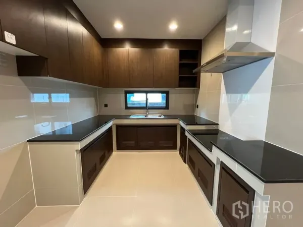 Detached House for rent in Bang Kapi, Bangkok - Separate U-shaped kitchen with dark cabinetry, range hood and a window over the sink.