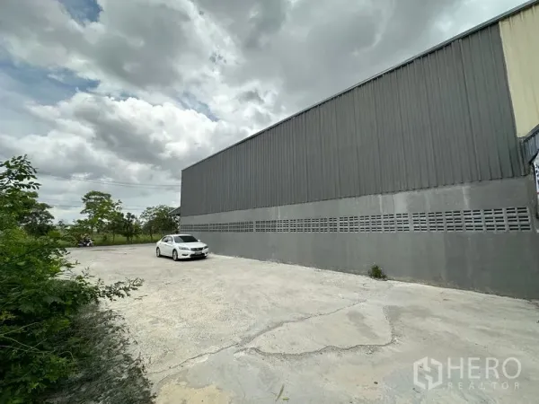 คลังสินค้า ให้เช่าในThanyaburi, Pathum Thani - มุมข้างโกดัง พร้อมลานจอดคอนกรีตกว้างและแนวต้นไม้