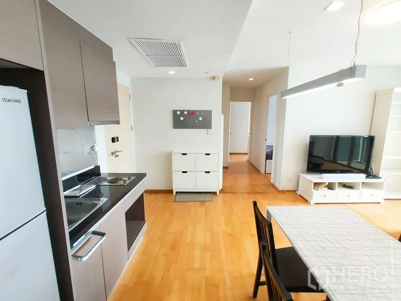 คอนโด ให้เช่าในKhlong Toei, Bangkok - ครัวขนาดกะทัดรัดพร้อมตู้แขวน อ่างล้างจาน เตาไฟฟ้า และตู้เย็น ข้างโต๊ะอาหาร