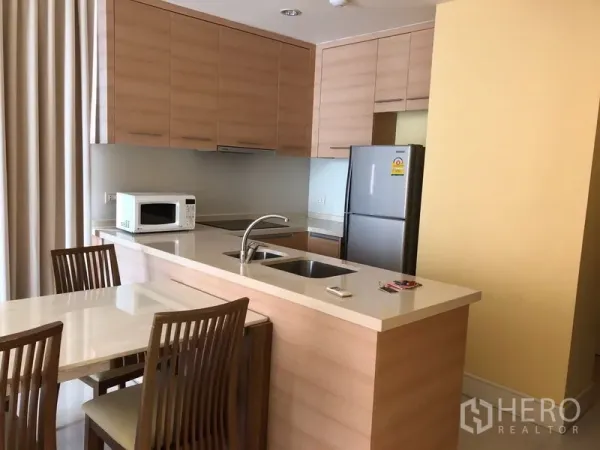 公寓 出租或出售在Khlong Toei, Bangkok - 开放式厨房，浅木色橱柜、吧台水槽和餐桌椅