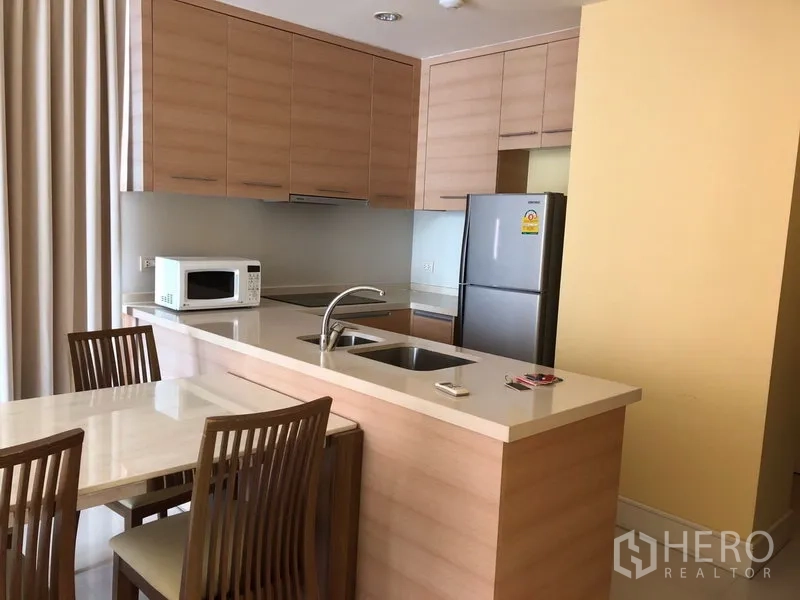 公寓 出租或出售在Khlong Toei, Bangkok - 开放式厨房，浅木色橱柜、吧台水槽和餐桌椅