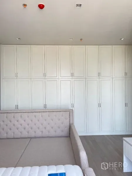 Condominium for rent in Bang Kho Laem, Bangkok - Wall of tall white wardrobes behind an upholstered bed in the bedroom.