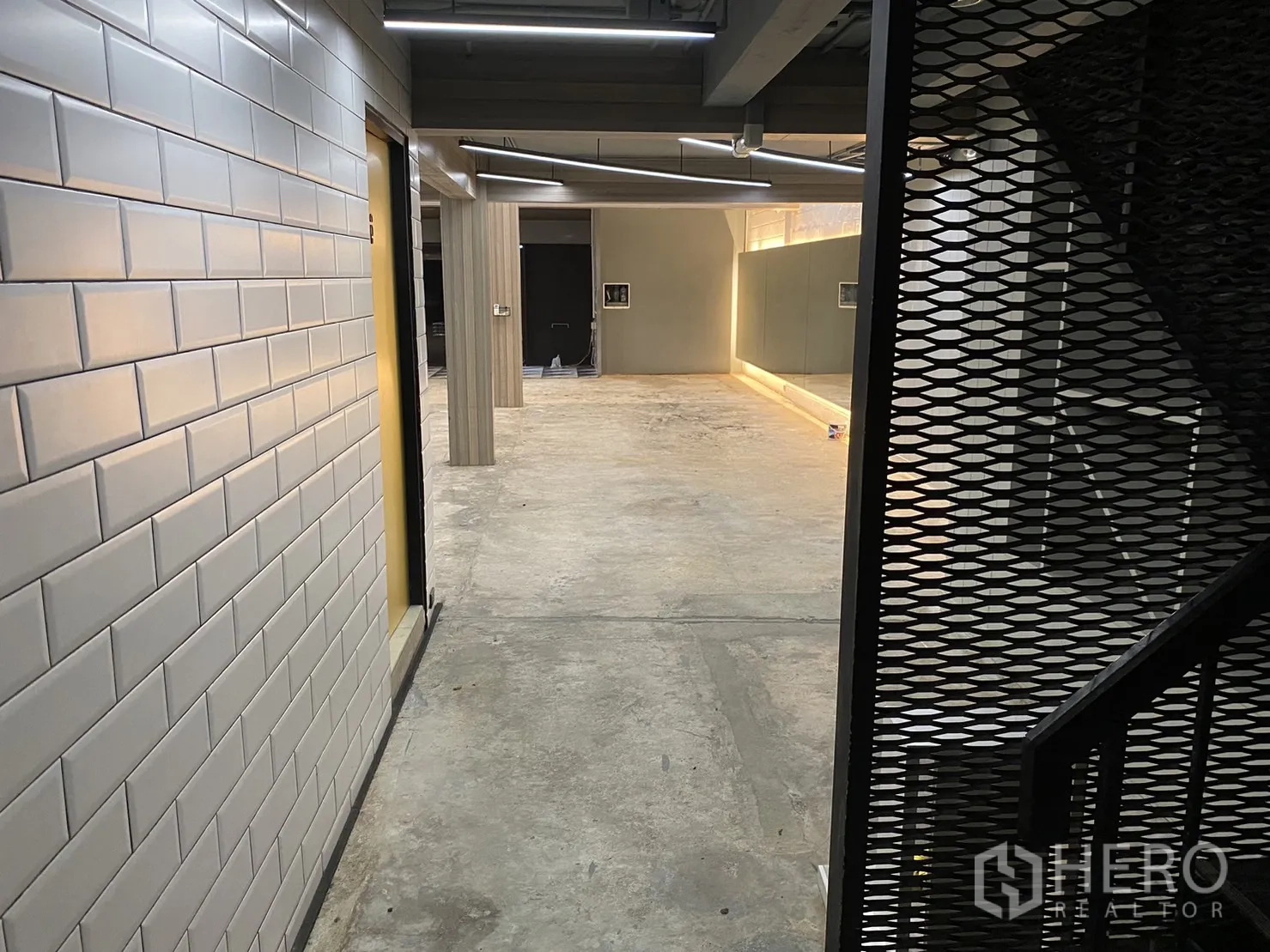 พื้นที่ขายปลีก ให้เช่าในPhaya Thai, Bangkok - โถงทางเดินผนังกระเบื้องซับเวย์สีขาว พร้อมบันไดเหล็กโปร่ง เปิดสู่พื้นที่โอเพ่นหลัก.