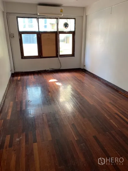 店屋 出租在Pathum Wan, Bangkok - 明亮房间，抛光木地板，墙装空调与正面窗户。