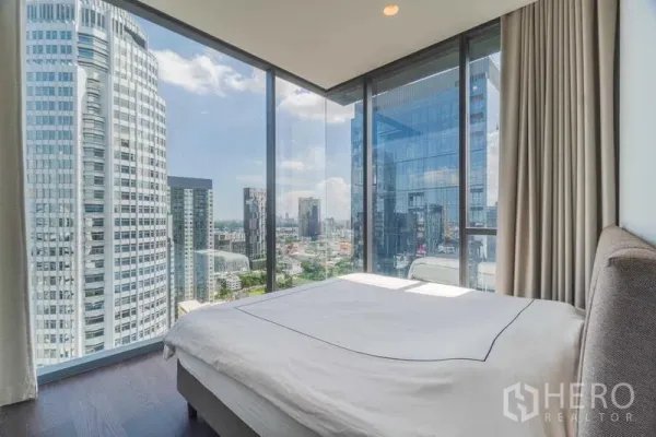 Condominium for rent or sale - Corner bedroom with floor-to-ceiling glass and panoramic Bangkok skyline view.