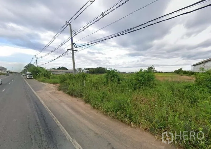 Land for sale in Chachoengsao - Paved main-road frontage with overhead power lines and grassy land along the shoulder.