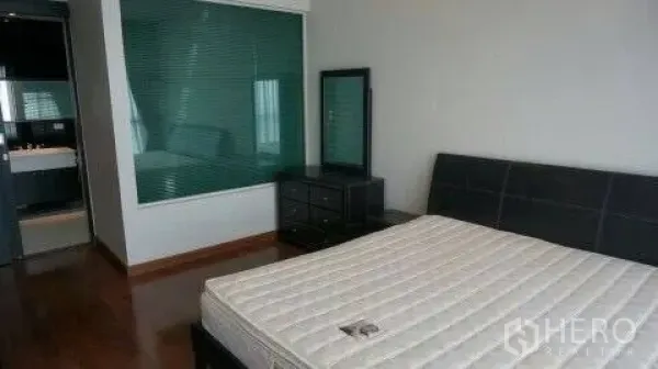Condominium for rent or sale in Pathum Wan, Bangkok - Bedroom with wood flooring, queen bed, dresser and a glass window to the ensuite bathroom