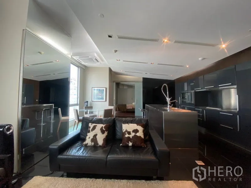 公寓 出租在Sathon, Bangkok - 开阔起居与厨房空间，皮沙发、不锈钢岛台与镜面质感饰面。