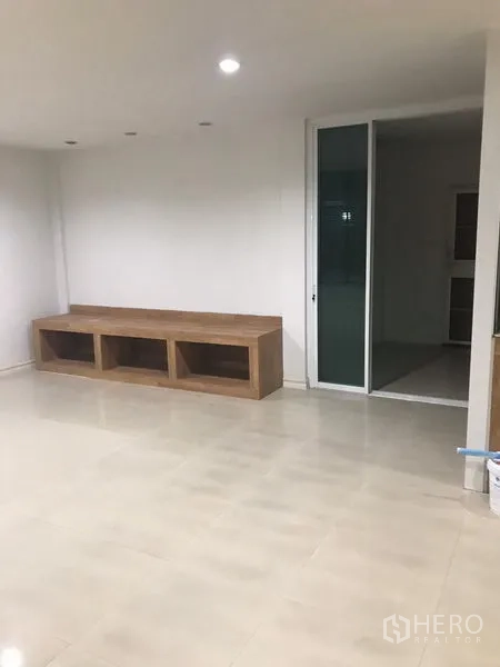 Detached House for rent in Din Daeng, Bangkok - Spacious living area with glossy tile floor, built-in wooden cabinet and a sliding glass door.