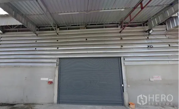 Warehouse for rent - Warehouse facade with metal canopy and large roller shutter loading door.