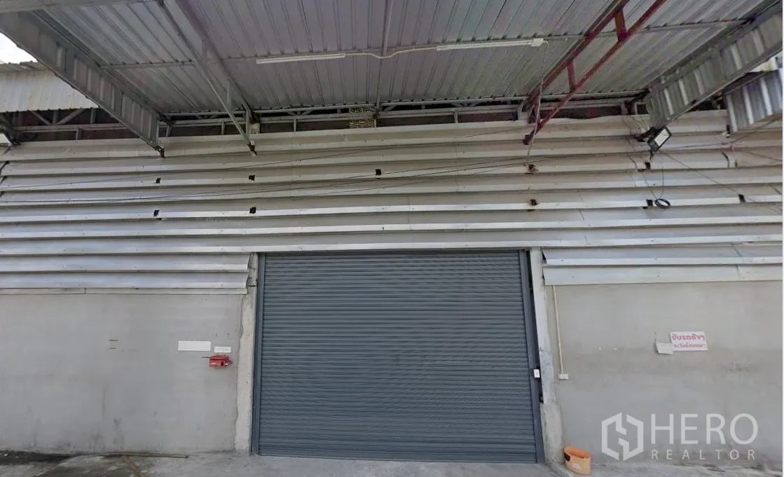 Warehouse for rent - Warehouse facade with metal canopy and large roller shutter loading door.