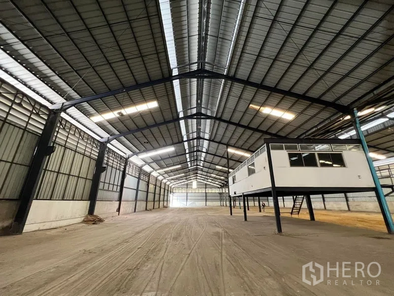 Warehouse for rent in Phra Samut Chedi, Samut Prakan - Warehouse interior featuring an elevated mezzanine office on stilts and wide floor space.