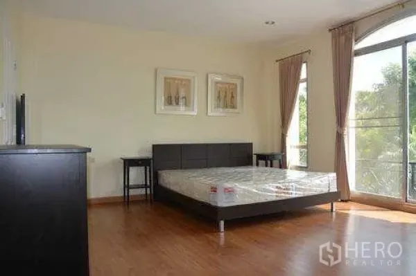 Home Office for rent in Wang Thonglang, Bangkok - Spacious bedroom with large window, brown curtains and double bed on wooden flooring in Wang Thonglang, Bangkok.