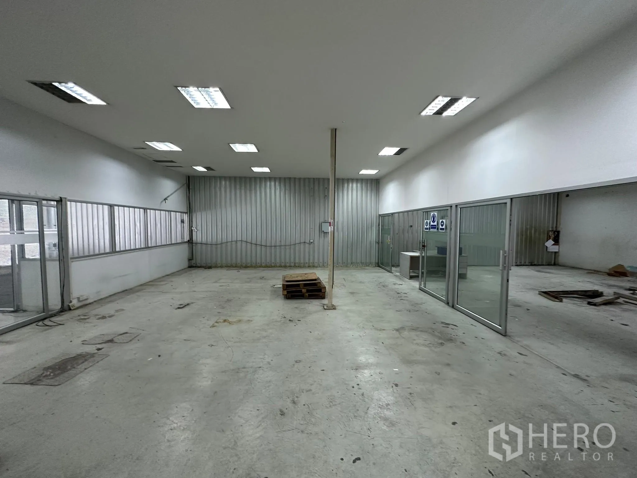 Warehouse for rent in Huai Khwang, Bangkok - Wide workshop zone with sliding glass doors and central support column.