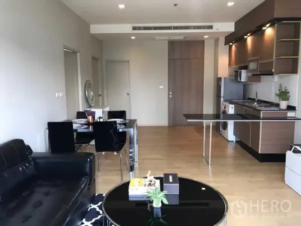 Condominium for rent in Watthana, Bangkok - Open-plan living room and modern kitchen with wood cabinets, built-in appliances, and a washing machine.