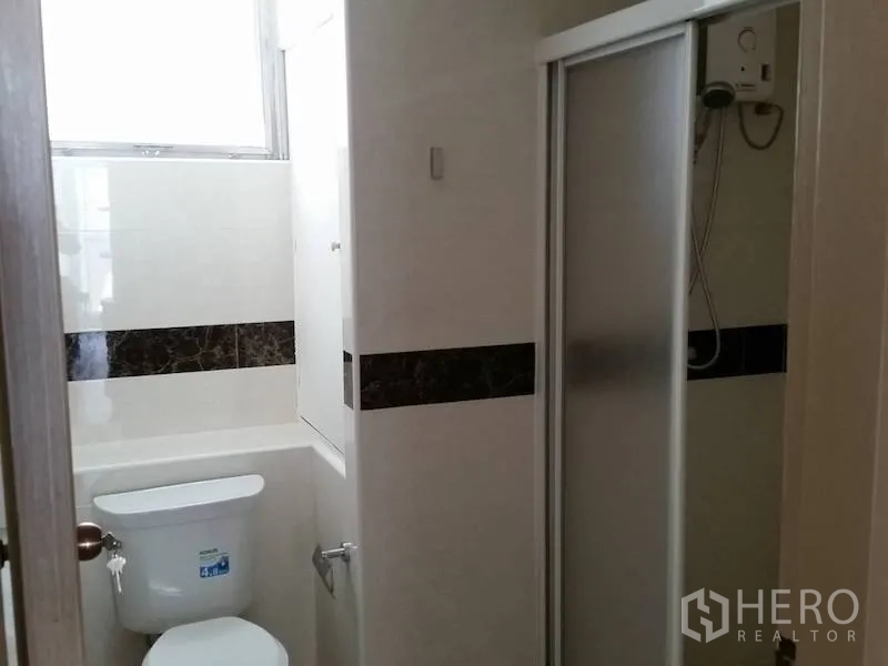 Condominium for rent in Watthana, Bangkok - Compact bathroom with toilet and a sliding-door shower enclosure.