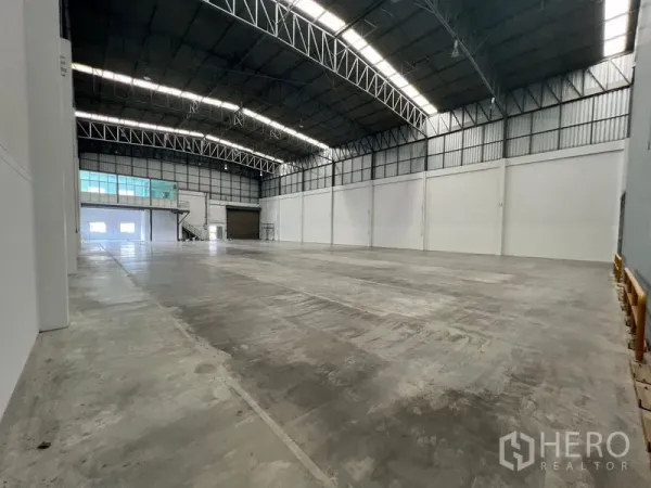 Warehouse for rent in Lat Krabang, Bangkok - Open-plan warehouse hall showing high clearance, skylight panels, and large roller shutter doors.
