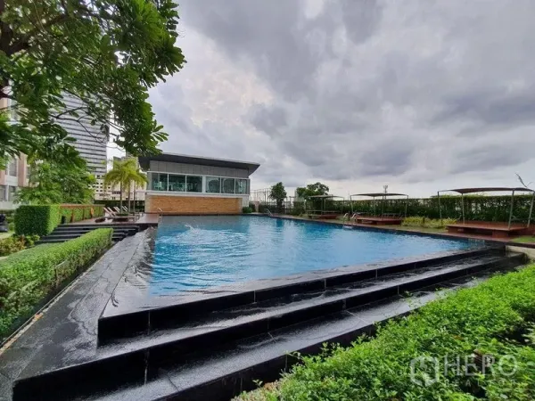 คอนโด ขาย - สระว่ายน้ำกลางแจ้งขอบอินฟินิตี้ รายล้อมด้วยสวนและดาดฟ้าใต้ท้องฟ้ามีเมฆ