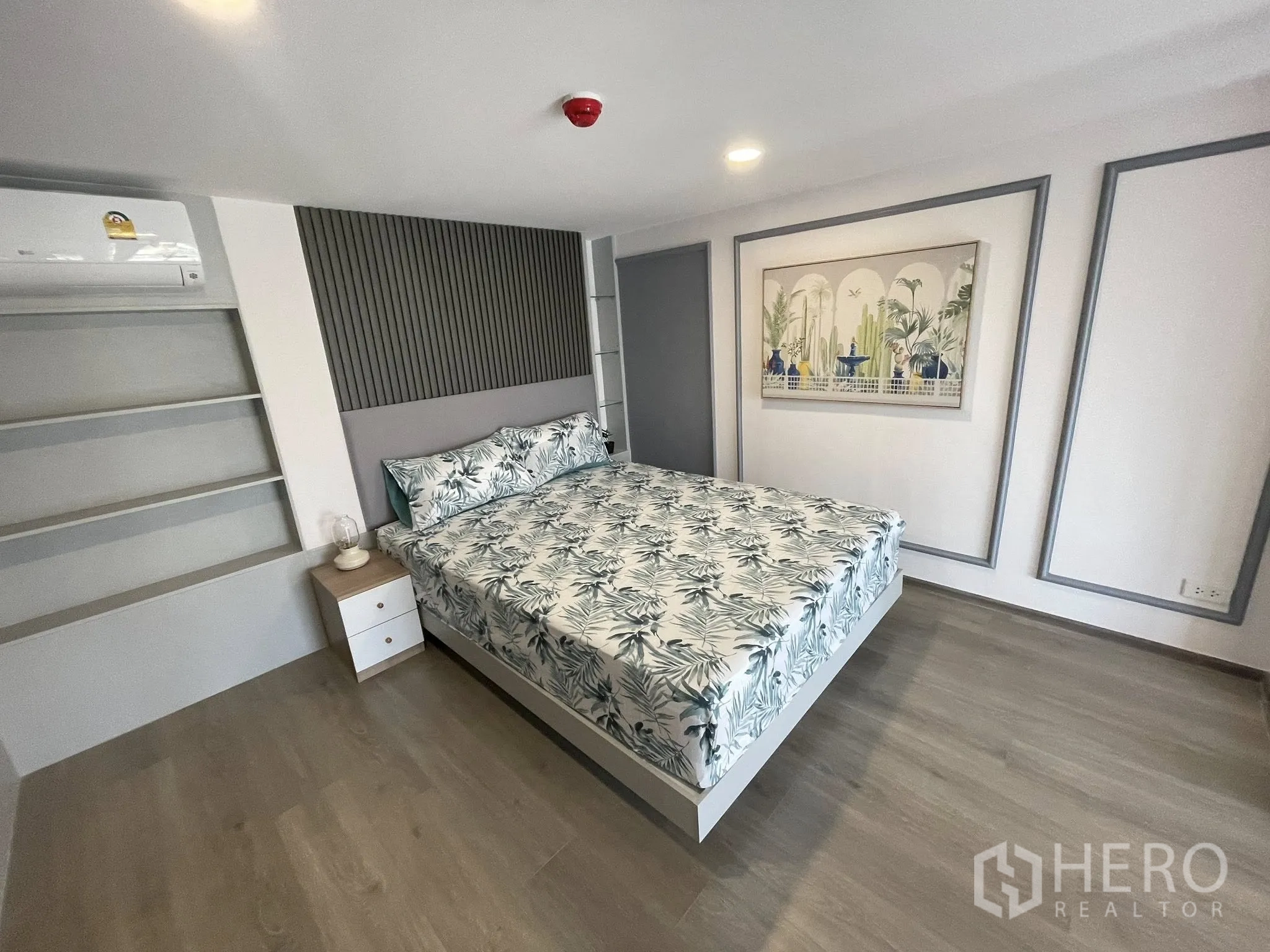 Condominium for rent in Khlong Toei, Bangkok - Mezzanine bedroom with double bed, built-in shelves, air conditioner, and wall art.