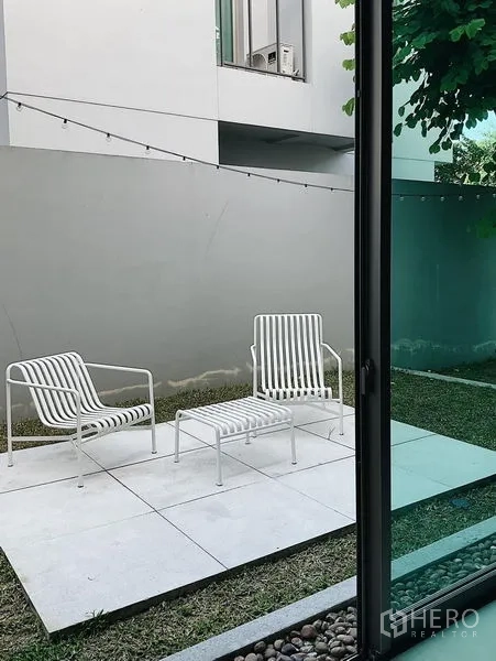 Detached House for sale in Bang Kapi, Bangkok - Private garden patio with white outdoor chairs on a tiled terrace.