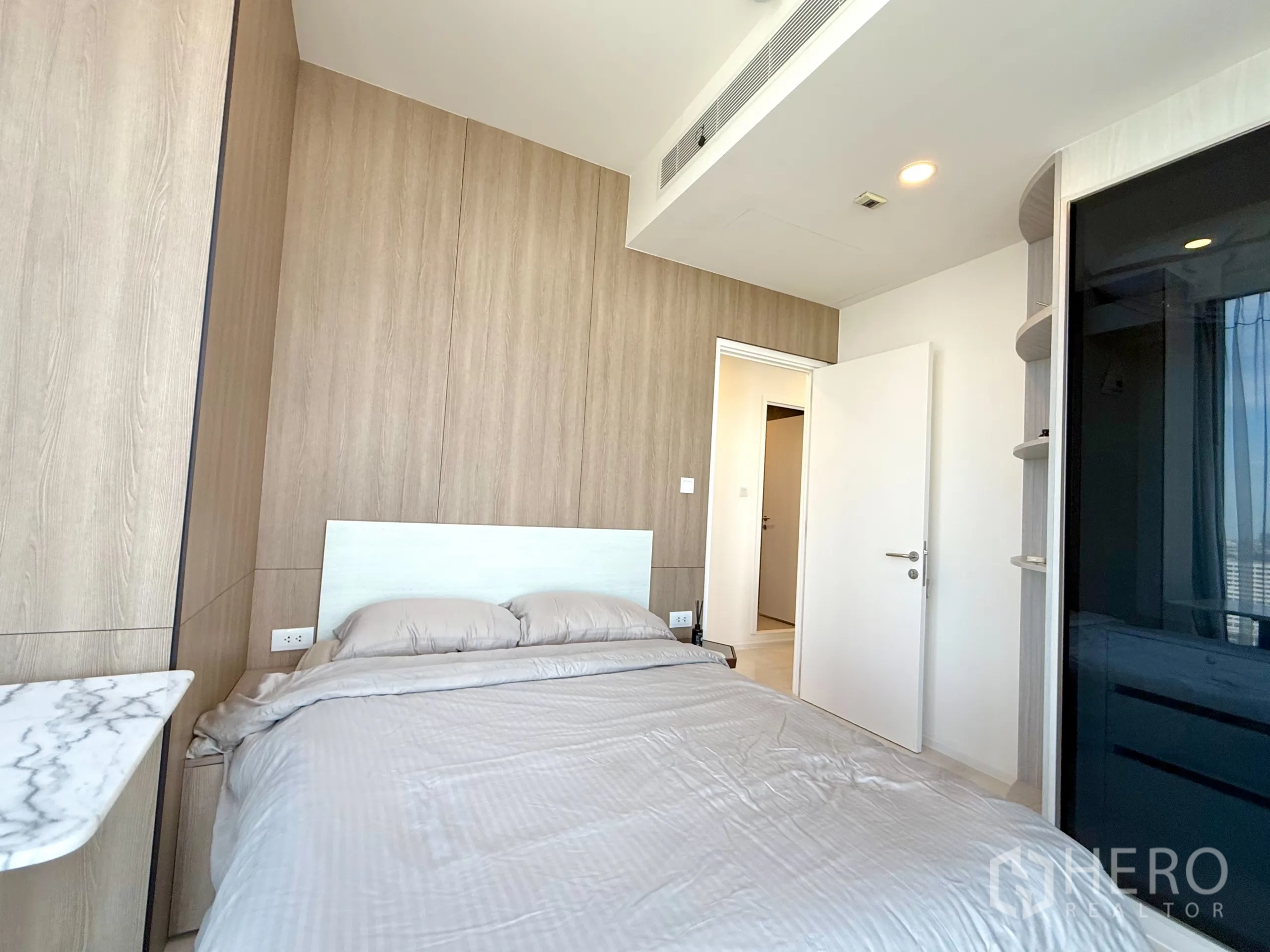 Condominium for sale in Chatuchak, Bangkok - Bedroom angle showing bed, white door, and storage cabinetry.