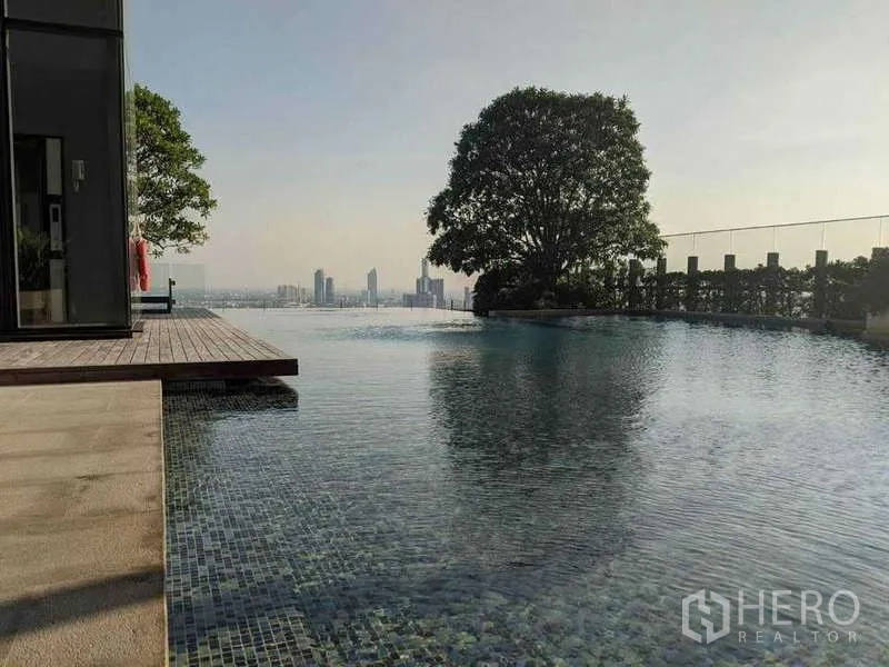 Condominium for rent in Sathon, Bangkok - Infinity-edge pool beside a deck and large tree overlooking the city.