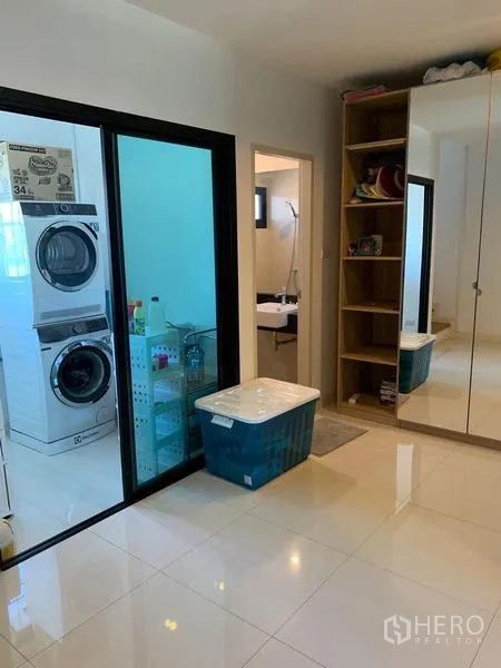 Office Space for sale in Saphan Sung, Bangkok - Utility zone with sliding glass door, stacked washer and dryer and storage shelves.